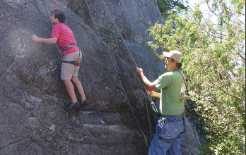 novice rockclimber helped by veteran